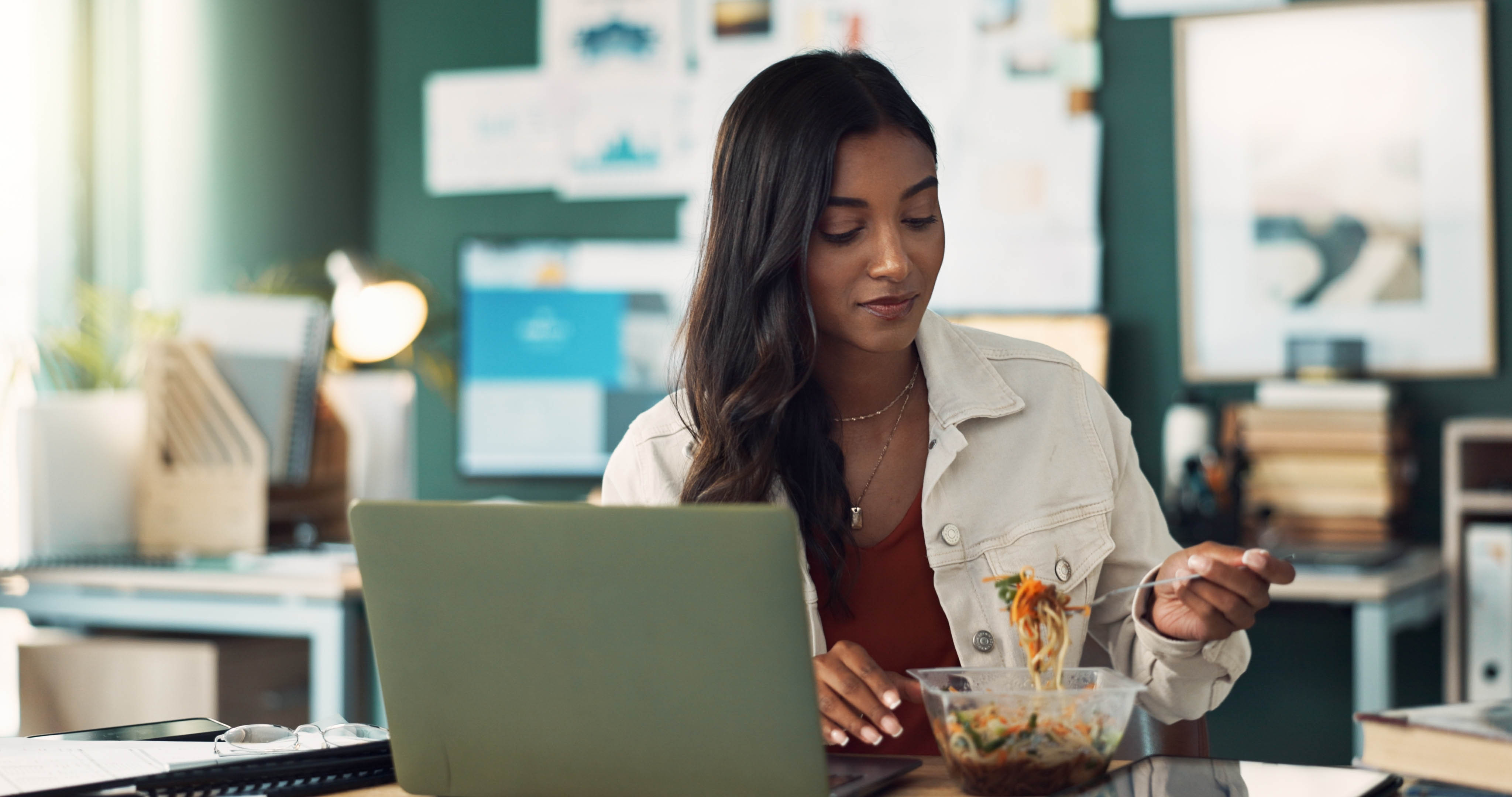Woman eating her healthy lunch at her desk while at work Woman eating her healthy lunch at her desk while at work
